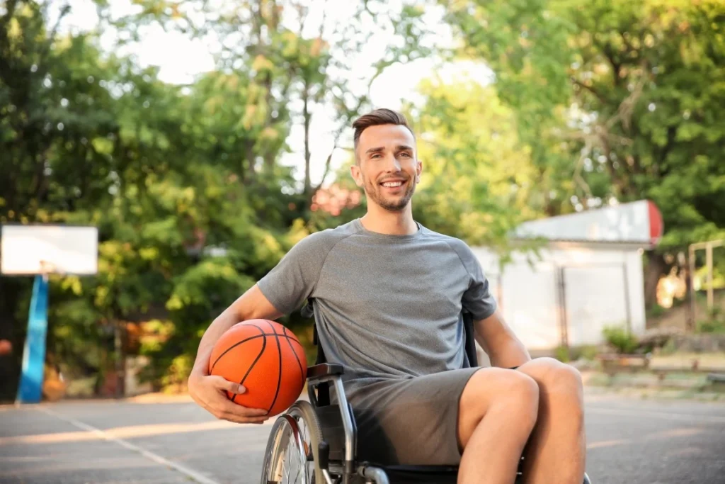 Disabled man in wheelchair holding basketball and smiling at camera