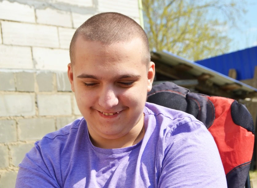 Boy with autism smiling and looking down past camera