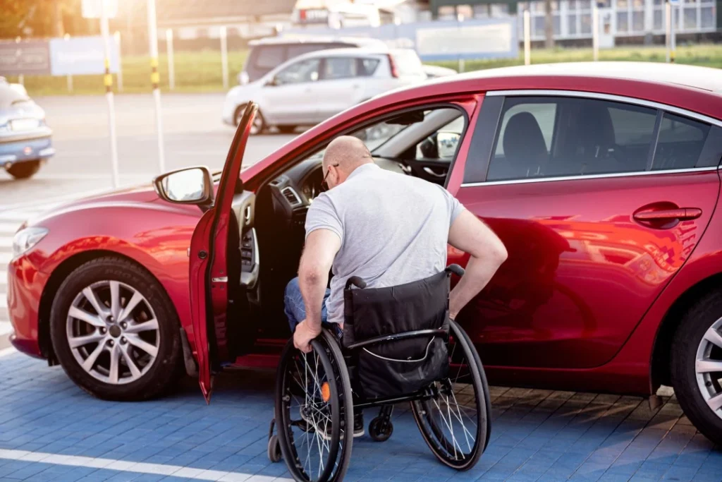 Man in wheelchair getting into car